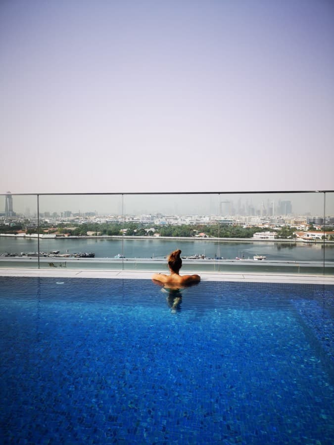 Daphné Saï dans une piscine à débordement face à la skyline, en travaillant depuis l'étranger