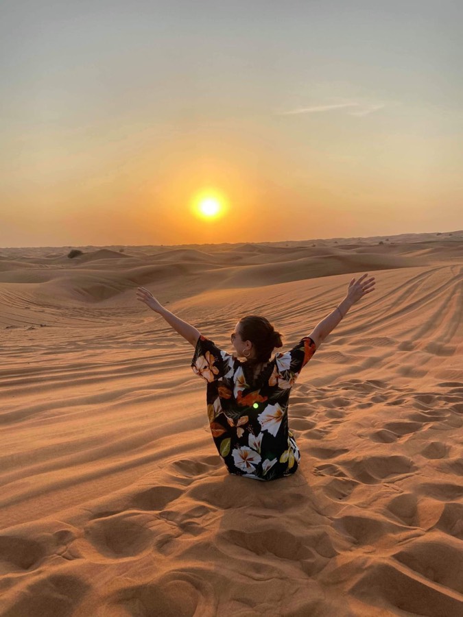 Daphné, bras levés dans le désert au coucher du soleil