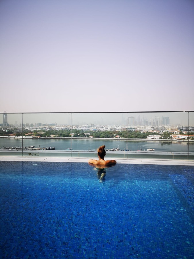 Daphné dans une piscine à débordement face à la skyline